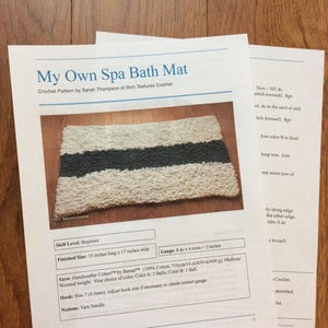 May include: Crochet pattern for a white and gray spa bath mat. The pattern includes instructions for creating a 35 inch by 17 inch mat using Bernat Handicrafter Cotton yarn. The pattern also includes gauge information and a list of materials needed.