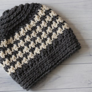 May include: A gray and white crocheted beanie hat with a chevron pattern.