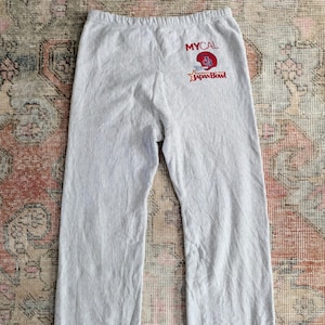 Puede incluir: Pantalones de chándal grises con el texto "MYCAL JAPAN BOWL" y un gráfico rojo y blanco de un casco de fútbol.
