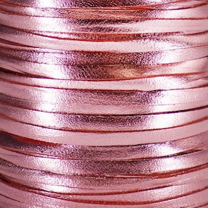 Könnte beinhalten: Nahaufnahme einer Spule mit rosafarbenem, metallischem Lederband. Das Band besteht aus dünnen Lederstreifen, die miteinander verwoben sind, um eine glatte, glänzende Oberfläche zu erzeugen.