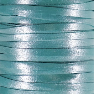 May include: A close-up of a roll of teal leather cord. The cord is smooth and shiny, with a slight sheen.