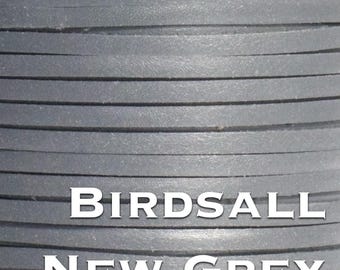 Könnte beinhalten: Nahaufnahme einer Spule mit flachen, grauen Lederstreifen. Das Leder hat eine einfarbige, neutrale Farbe und die Textur erscheint glatt. Der Text "BIRDSALL NEW GREY" ist weiß gedruckt.