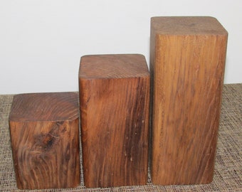 May include: Three wooden display risers of varying sizes, made of natural wood with a rustic finish. The risers are arranged in a staircase formation, with the largest riser at the back and the smallest riser at the front.