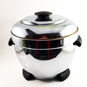 May include: A silver ice bucket with a black lid and black feet. The bucket has a shiny, reflective surface.