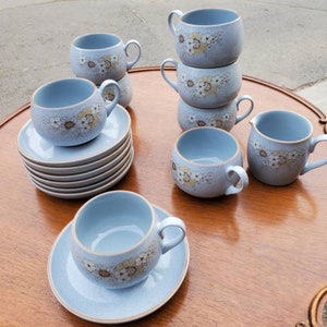 May include: A set of blue and white floral teacups and saucers with a cream jug. The cups and saucers feature a delicate floral pattern in shades of brown and yellow.