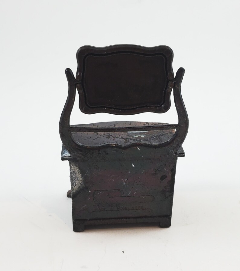 May include: Black metal pencil sharpener shaped like a vanity with a mirror. The sharpener has a drawer and a small shelf. The text "MADE IN JAPAN" is visible on the bottom.
