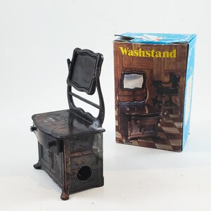May include: A vintage metal pencil sharpener shaped like a washstand with a mirror. The sharpener is brown and has a small drawer. The box says "Washstand" and "No. 6024".