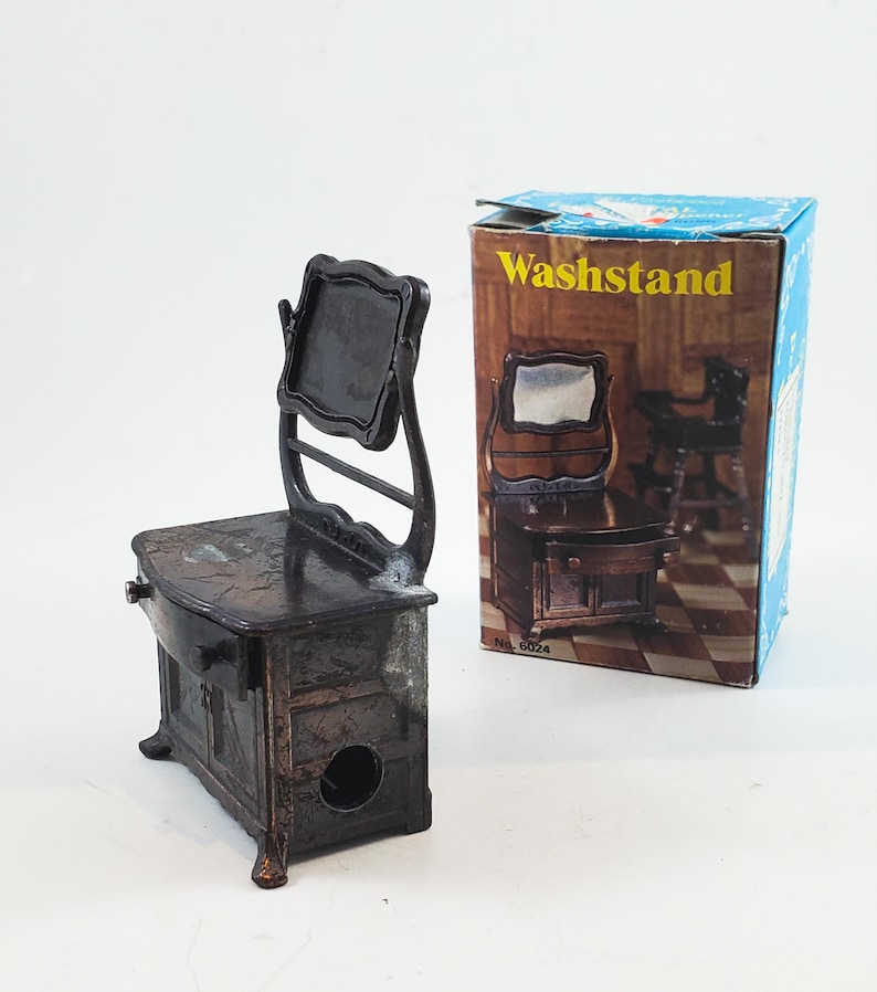 May include: A vintage metal pencil sharpener shaped like a washstand with a mirror. The sharpener is brown and has a small drawer. The box says "Washstand" and "No. 6024".