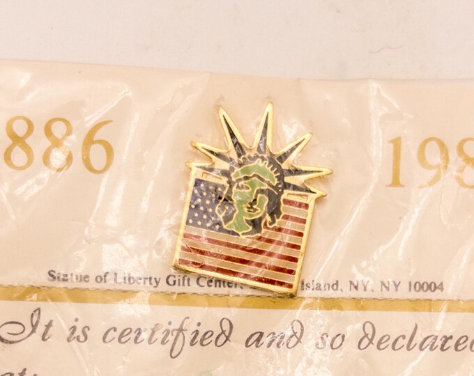 1986 Statue of Liberty Centennial lapel pin with certificate, round campaign button teal and white graphic of old time film camera