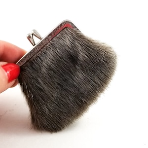 May include: A small, grey, furry coin purse with a silver metal frame.