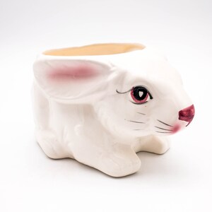 May include: White ceramic bunny planter with pink ears and painted black eyes and a red nose.