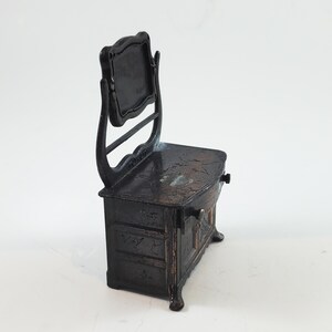 May include: A black metal vanity with a mirror and a drawer. The vanity is a vintage pencil sharpener.
