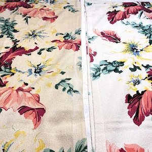 May include: Two floral fabric panels. One panel is a cream color with a pattern of large pink, red, yellow, and blue flowers and green leaves. The other panel is white with the same floral pattern.