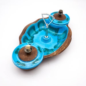 May include: A blue and brown ceramic serving dish with two smaller dishes attached. The larger dish has a swirl design and the smaller dishes have lids.