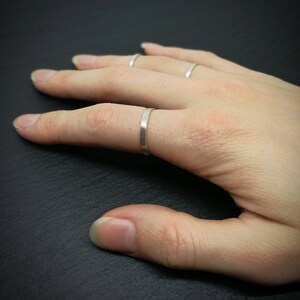 Könnte beinhalten: Eine Hand trägt vier dünne silberne Ringe an verschiedenen Fingern.