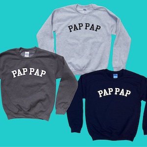 May include: Three sweatshirts in different colors: gray, dark gray, and navy blue. Each sweatshirt has the text "PAP PAP" printed on the front in white.