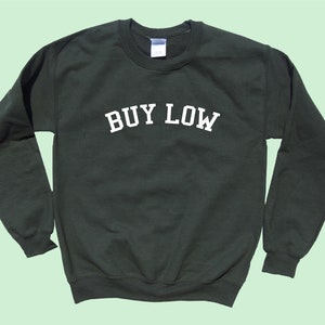 May include: A dark green sweatshirt with the text "BUY LOW" in white lettering.