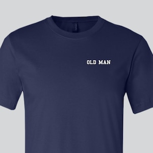 May include: A navy blue t-shirt with the text "OLD MAN" printed in white on the front.