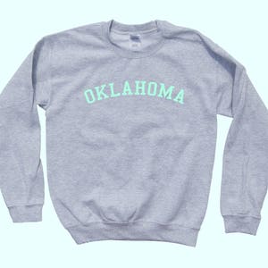 May include: A gray sweatshirt with the word "OKLAHOMA" printed in light green on the front.