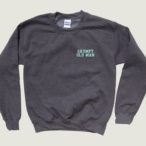 May include: A dark gray sweatshirt with the text "GRUMPY OLD MAN" in light blue on the front.