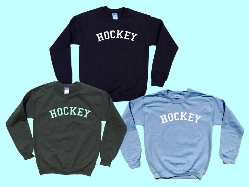 Pu&ograve; includere: Tre felpe in nero, verde e azzurro chiaro con la scritta "HOCKEY" stampata in bianco sul davanti.