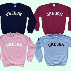 May include: Four crewneck sweatshirts in different colors with the word "OREGON" printed in white or black across the chest.
