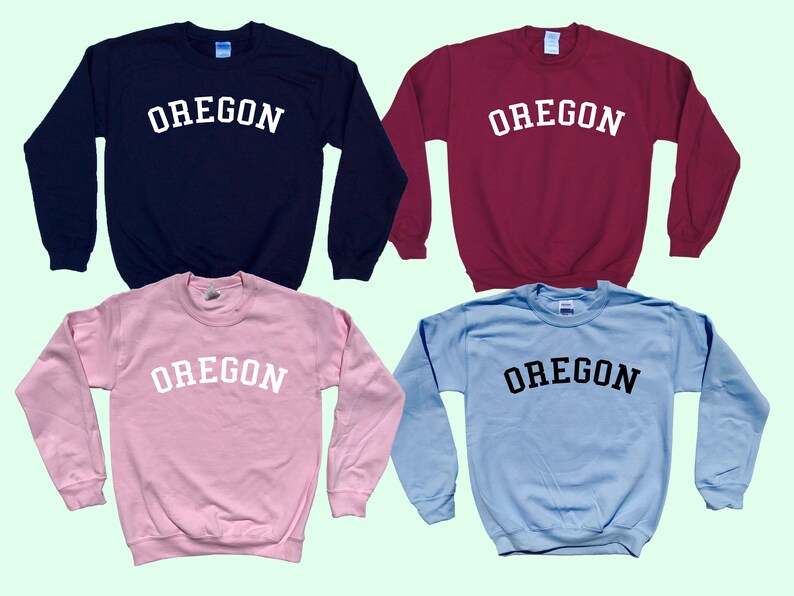May include: Four crewneck sweatshirts in different colors with the word "OREGON" printed in white or black across the chest.