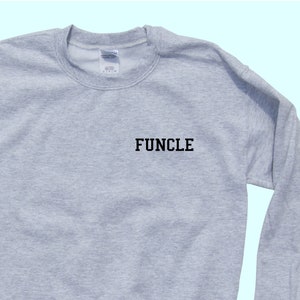 May include: A gray sweatshirt with the word "FUNCLE" printed in black on the front.