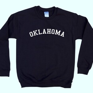 May include: Black long-sleeved sweatshirt with white text that reads "OKLAHOMA" across the chest.