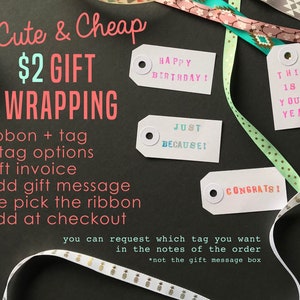 May include: Cute & Cheap $2 Gift Wrapping.  A black background with white text and four gift tags with colorful text. The tags say "Happy Birthday!" "This is your year!" "Just because!" and "Congrats!"