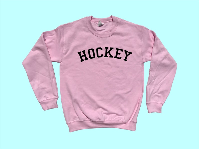 Pu&ograve; includere: Una felpa rosa con la scritta "HOCKEY" stampata in nero sul davanti.