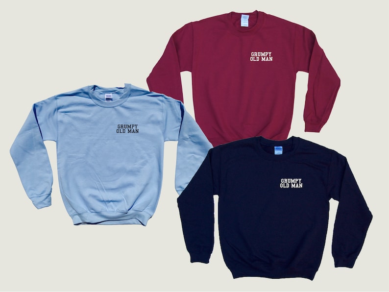 May include: Three sweatshirts in different colors: light blue, maroon, and navy blue. Each sweatshirt has the text "GRUMPY OLD MAN" embroidered on the front in white.