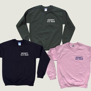 May include: Three sweatshirts in different colors: black, green, and pink. Each sweatshirt has the text "GRUMPY OLD MAN" embroidered on the front in white or blue.