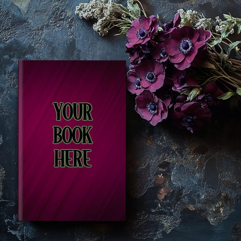 Może przedstawiać: Okładka książki w ciemnym kolorze czerwonym z tekstem "YOUR BOOK HERE" w czarnych literach. Książka leży na ciemnoszarej, fakturowanej powierzchni z bukietem ciemnofioletowych kwiat&oacute;w.