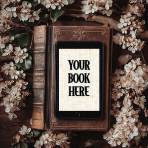 Może przedstawiać: Antyczna książka z tabletem na g&oacute;rze. Ekran tabletu wyświetla tekst "YOUR BOOK HERE" czarnym kolorem na białym tle. Książka i tablet są otoczone białymi kwiatami.
