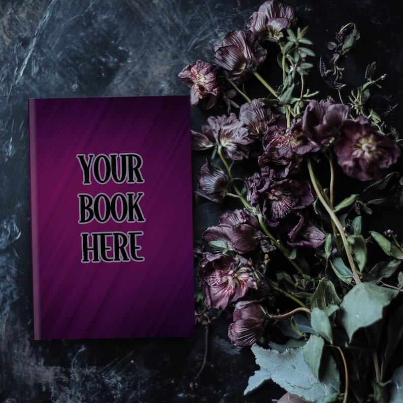 Może przedstawiać: Makieta okładki książki w ciemnym fioletowym kolorze z tekstem "YOUR BOOK HERE" na ciemnym tle z suszonymi fioletowymi kwiatami.