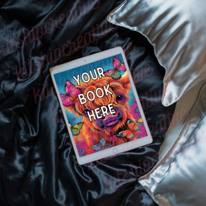 K&ouml;nnte beinhalten: Ein digitales Tablet mit einer farbenfrohen Illustration einer schottischen Hochlandkuh mit Schmetterlingen. Der Text "YOUR BOOK HERE" wird auf dem Tablet angezeigt.