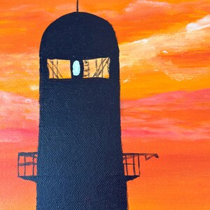 May include: A black silhouette of a tall tower with a cross on top against a bright orange and pink sunset sky. The tower has two windows and a small balcony.