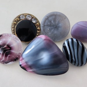 May include: Six different buttons in various colors and patterns. The buttons are made of glass and have a shiny finish. The buttons are round, oval, and triangular in shape.