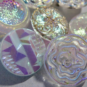 Peut inclure: Assortiment de boutons en verre irisé avec différents motifs, dont un motif géométrique, un motif floral et un motif en spirale.