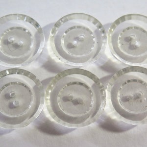 以下が含まれることがあります： 2つの穴がそれぞれ開いた透明なプラスチックボタンが6つ。ボタンは縁が高く、滑らかで光沢のある表面をしています。