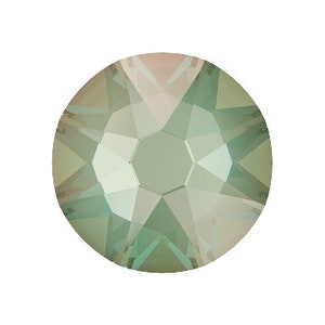 May include: A round, faceted, light green crystal rhinestone with a subtle iridescent shimmer.