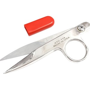 May include: Silver-coloured thread snips with a red plastic cap. The snips have a small ring handle and the text "ATC 114 Made in USA" is engraved on the side.