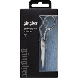 May include: A silver embroidery scissors in a black and silver package. The package has the text "gingher" and "embroidery scissors 4" printed on it.