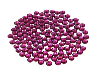Pode incluir: Um grande grupo de pequenos strass redondos de cor magenta. Os strass estão espalhados sobre um fundo branco.