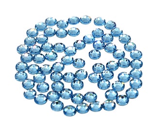 Pode incluir: Uma dispersão de strass azul claro, dispostos em um padrão circular sobre um fundo branco.