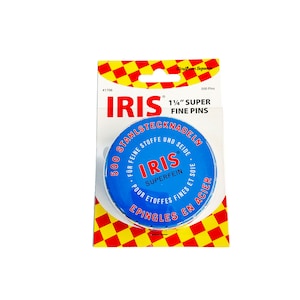 May include: A blue and white round tin of 500 1 1/2 inch super fine pins. The tin has the text "IRIS" in red and white lettering. The text "500 Stahlstecknadeln" is in black lettering on the tin. The text "Für feine Stoffe und Seide" is in black lettering on the tin. The text "IRIS Superfein" is in red and white lettering on the tin. The text "Pour étoffes fines et soie" is in black lettering on the tin. The text "Epingles en acier" is in black lettering on the tin.