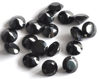 May include: A collection of 16 black round faceted gemstones. The gemstones are arranged in a random pattern on a white surface.