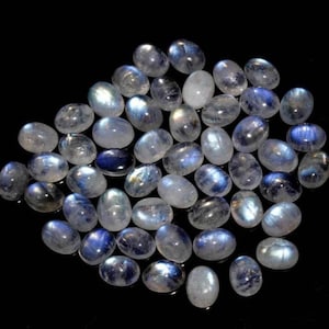 Puede incluir: Una colección de cabujones de piedra lunar de forma ovalada, de color blanco lechoso con destellos azules iridiscentes.