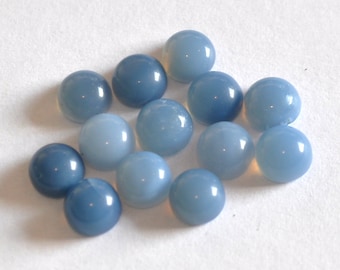 May include: A group of 13 round, blue opal cabochons, ranging in shades of light to dark blue. The cabochons are smooth and polished, with a slight sheen.